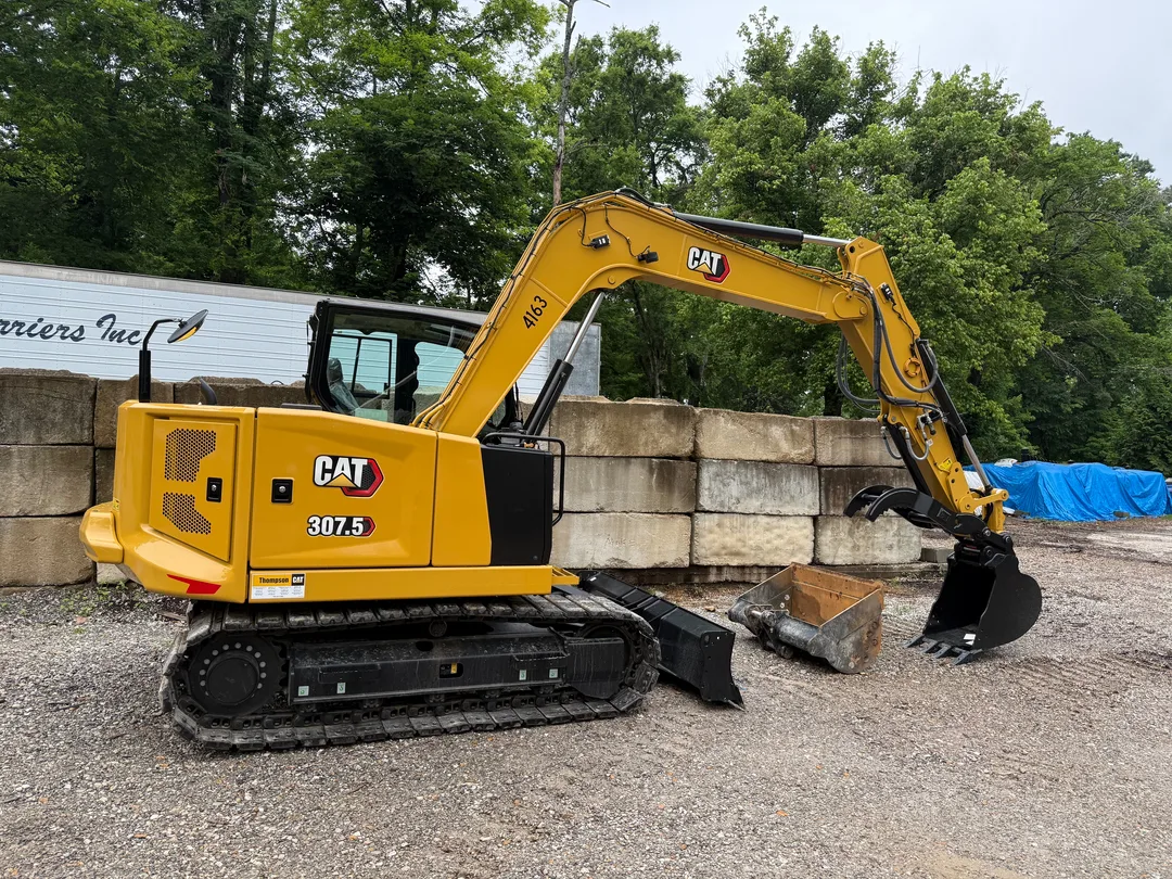 CAT excavator working at a block retaining wall